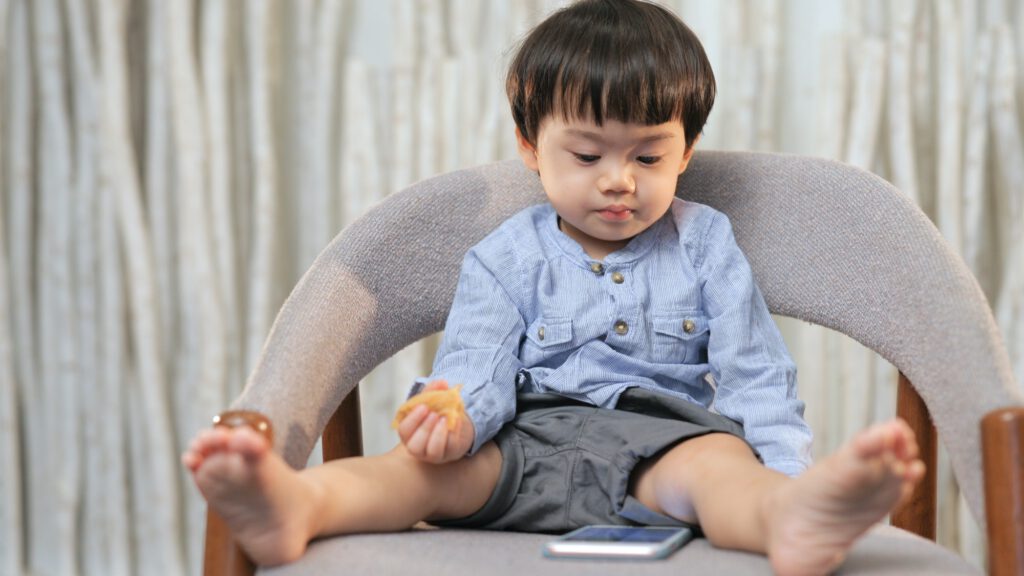 Asian kids holding a cake and looking at the mobile phone